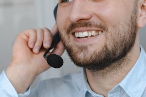 Close-up of a smiling customer support agent wearing a headset microphone.